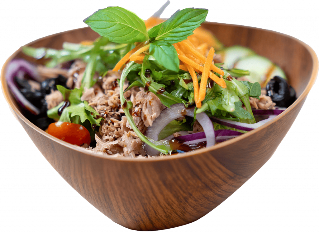 Thunfischsalat angerichtet in Holzschale, dekoriert mit zarten Karottenspänen und Basilikum