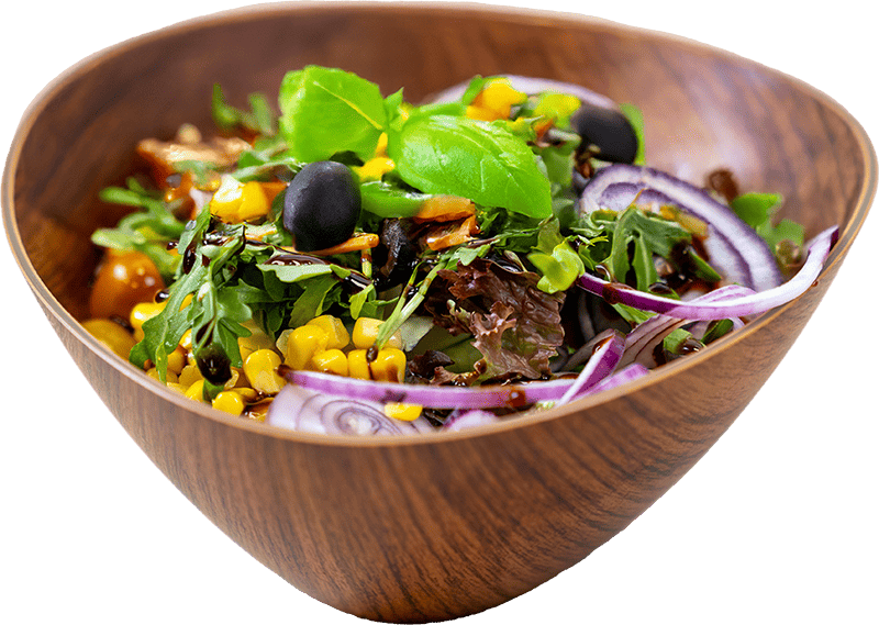 Schöne Holzschalte mit Salat mit Rucola, Oliven, roten Zwiebeln und Mais, garniert mit einem Basilikumblatt