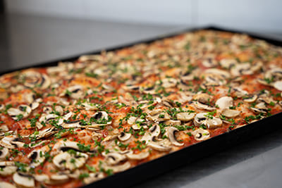 Blechpizza mit Pilzen auf Tomatensoße