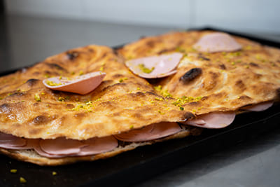 Blechpizza mit Mortadella, Stracciatella-Käse und Pistazienpesto