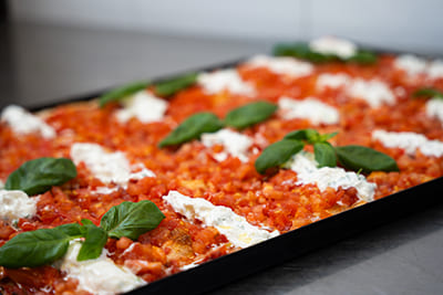 Blechpizza mit gewürfelten Cocktailtomaten und Stracciatella-Käse