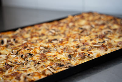 Blechpizza mit Hackfleisch, Champignons und Mozzarella, garniert mit Petersilie