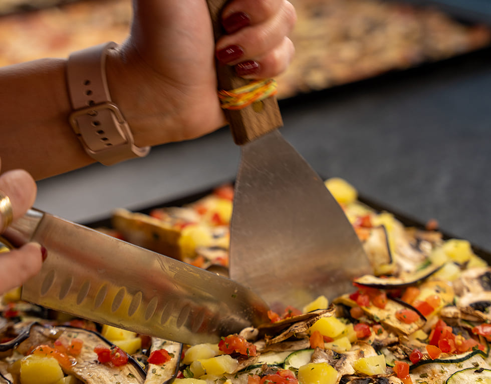 Mitarbeiterin schneidet Pizza